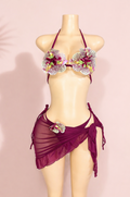 Purple bikini set with floral embellishments on a mannequin against a pink background